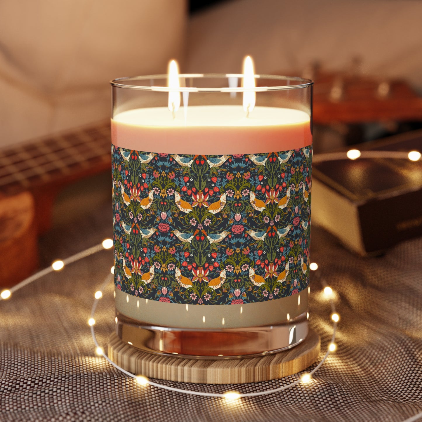 Candle with floral patterned wick on a textured surface with lights.