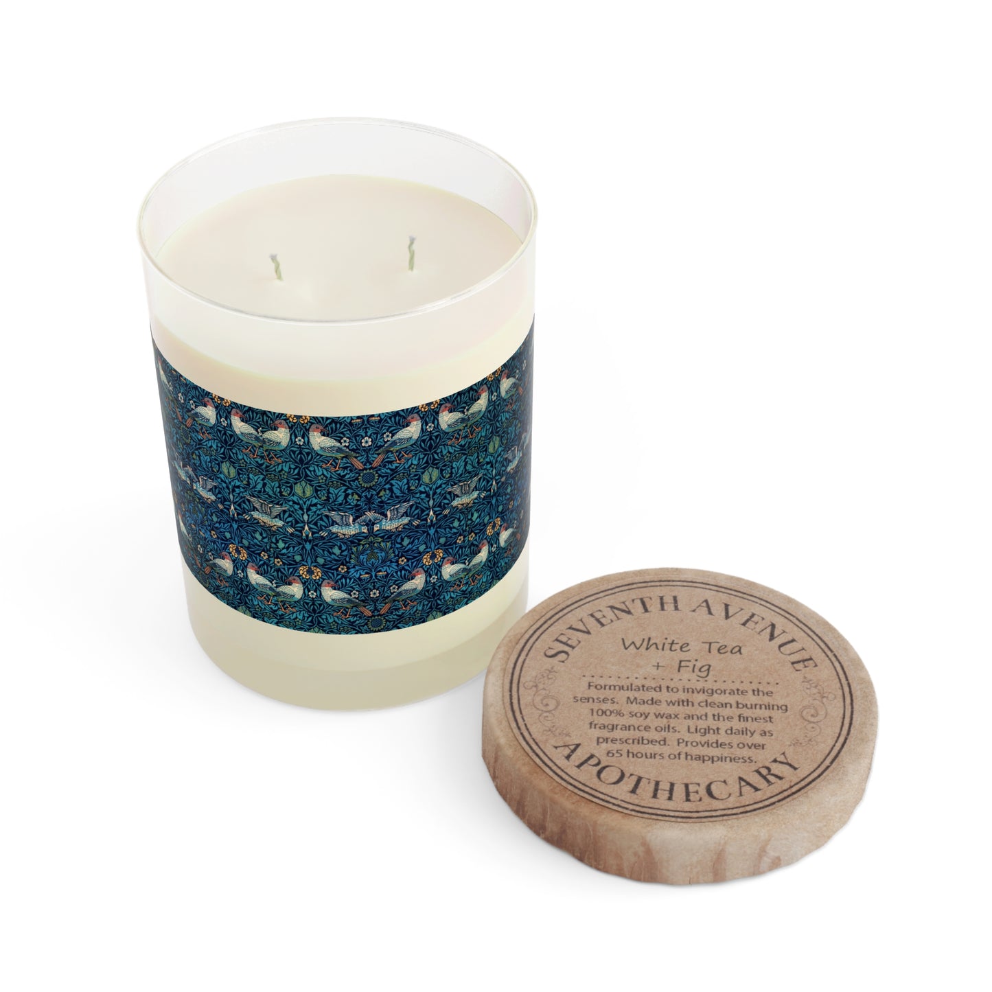 A clear glass candle with a bluebird pattern on the lid, alongside a brown cardboard lid with the text 'Seventh Ave White Tea & Fig Candle'.