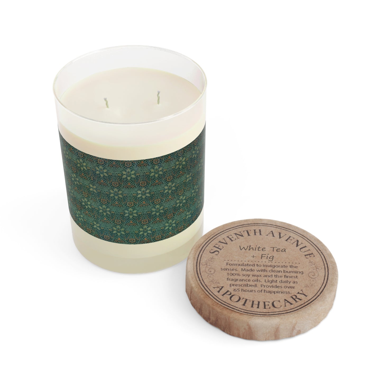 A clear glass candle with a beige and green floral patterned lid, labeled 'Seventh Ave White Tea & Fig' with a brown wick and a small round brown cardboard lid on top.