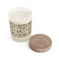 A two-wick scented candle in a clear glass vessel with cream-colored wax and a decorative botanical label, shown next to its round wooden lid on a white background. The lid is printed with the brand name 'Apothecary' and scent details.