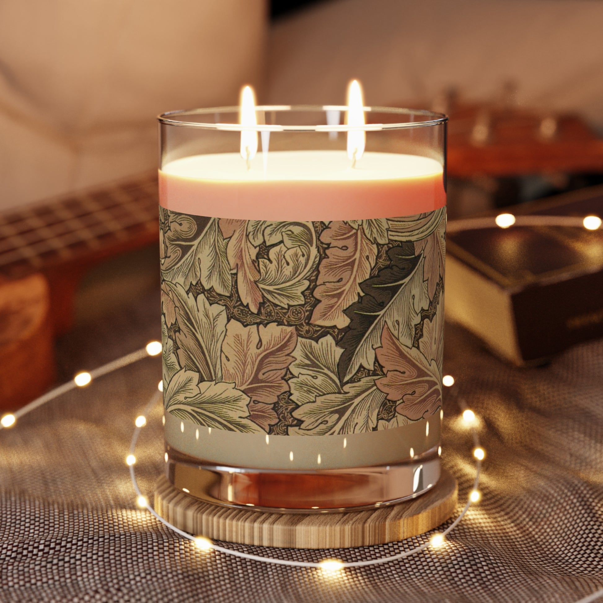 A brown luxury scented candle with a floral William Morris & Co patterned label, alongside a brown cardboard lid with text. The candle is placed in a clear glass jar.