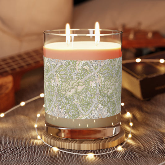 A luxury scented candle with a green and brown William Morris & Co floral patterned wrap around it, labeled 'Brook' from the Windrush Collection. The candle is in a clear jar with a brown cardboard lid.