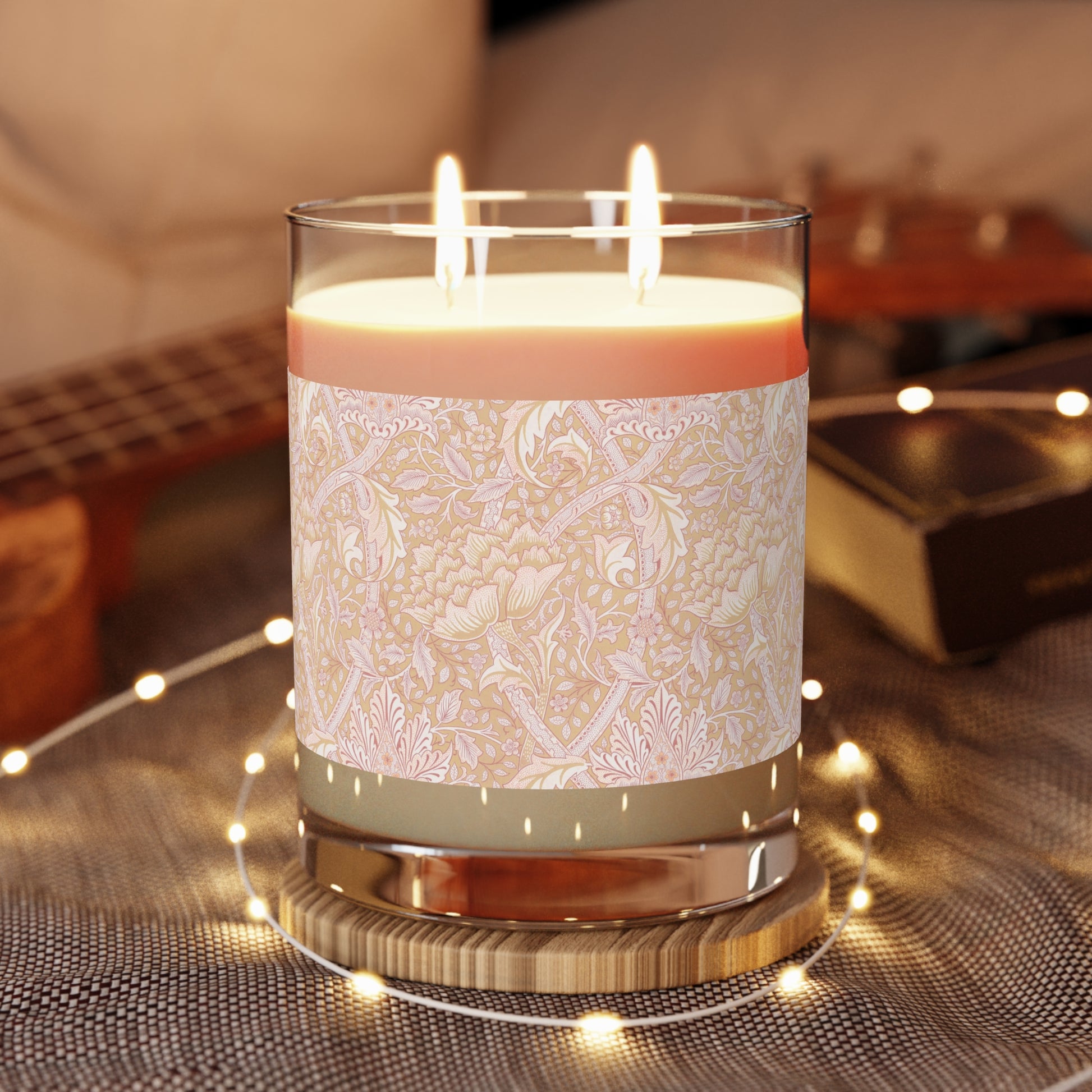 A luxury scented candle with a floral William Morris & Co pattern wrap around the glass jar, alongside a brown cardboard lid.