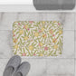 Floral-patterned bath mat on a tiled bathroom floor with slippers and a towel.