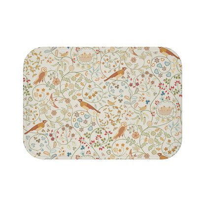 A microfibre bath mat with a floral and bird pattern inspired by William Morris, in a beige, green, and brown color palette.