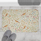 A microfibre bath mat with a floral and bird pattern inspired by William Morris, in a beige, green, and brown color palette.