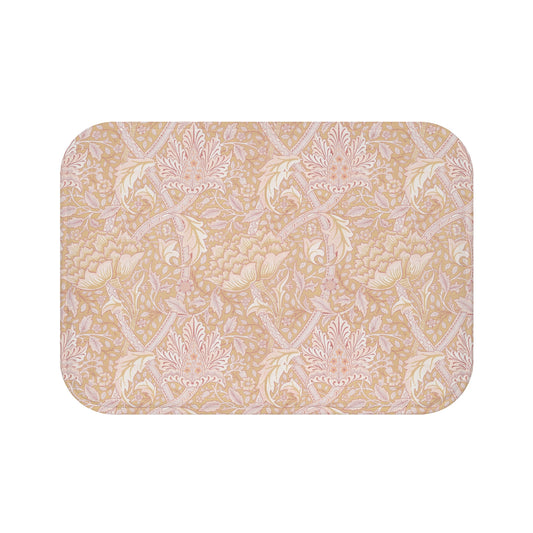 A rectangular microfibre bath mat with a floral pattern inspired by William Morris, in beige, pink, and green colors.