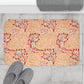 Rectangular microfibre bath mat with an orange and white floral pattern inspired by William Morris' Apple Collection.