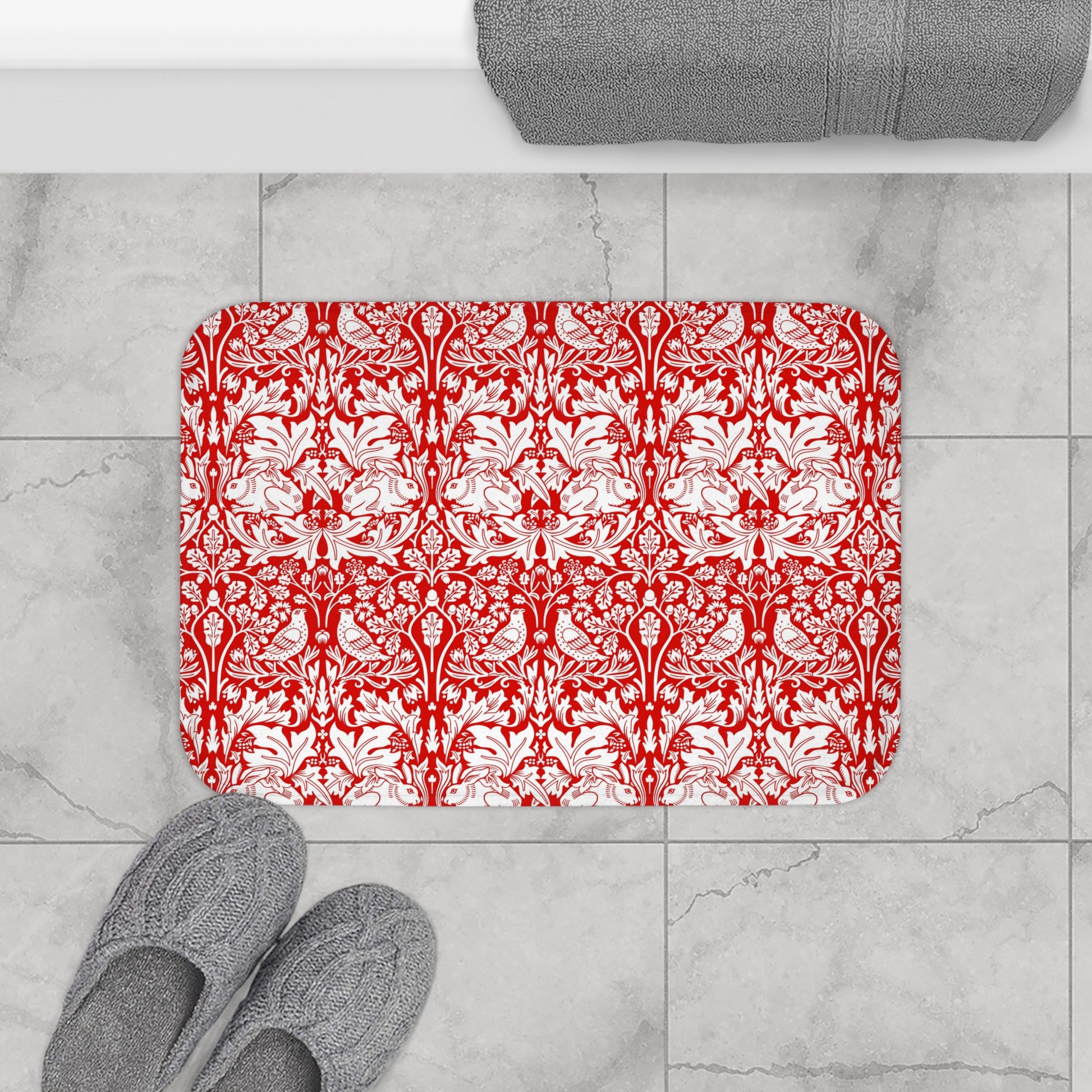 Decorative red and white patterned rug on a marble floor with gray slippers and a towel.