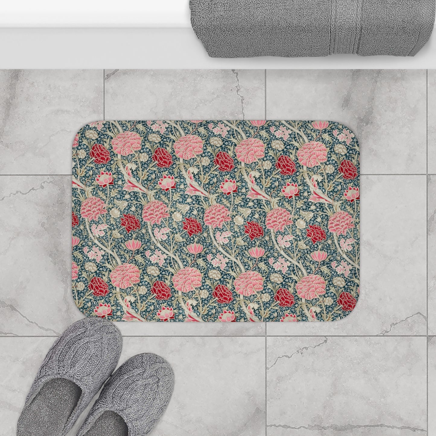 Floral patterned bath mat on a tiled floor with slippers nearby