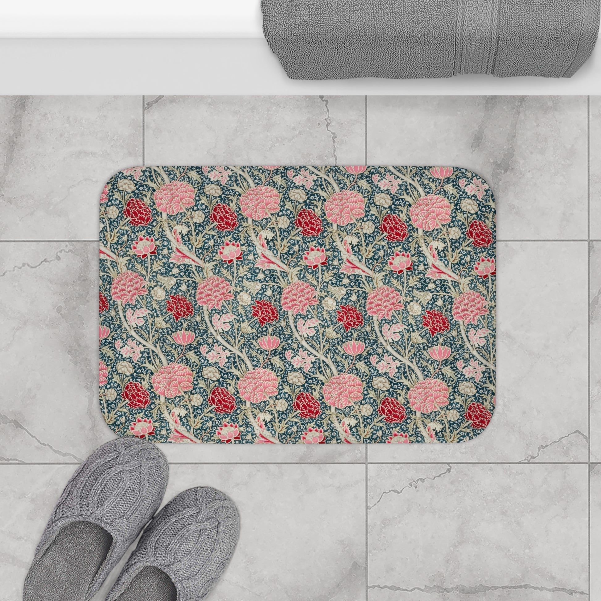 Floral patterned bath mat on a tiled floor with slippers nearby