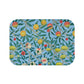 A rectangular microfibre bath mat with a floral pattern featuring fruits and leaves on a blue background.