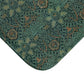 Rectangular microfibre bath mat with an intricate floral pattern in green and gold colours, with rounded edges and a non-slip black backing from William Morris.