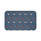 A rectangular microfibre bath mat with a floral pattern inspired by William Morris, predominantly blue with red and white accents.