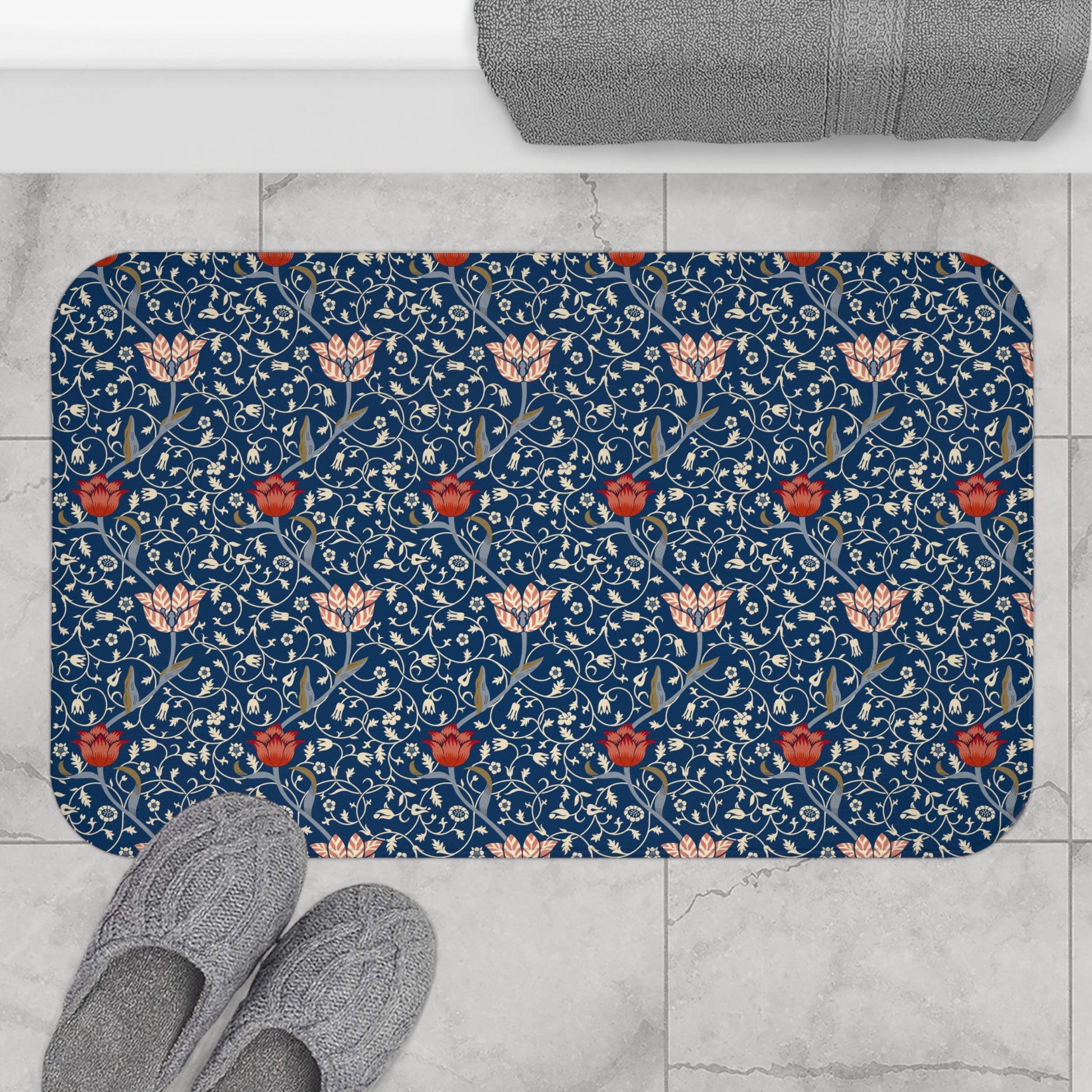 A rectangular microfibre bath mat with a floral pattern inspired by William Morris, predominantly blue with red and white accents.