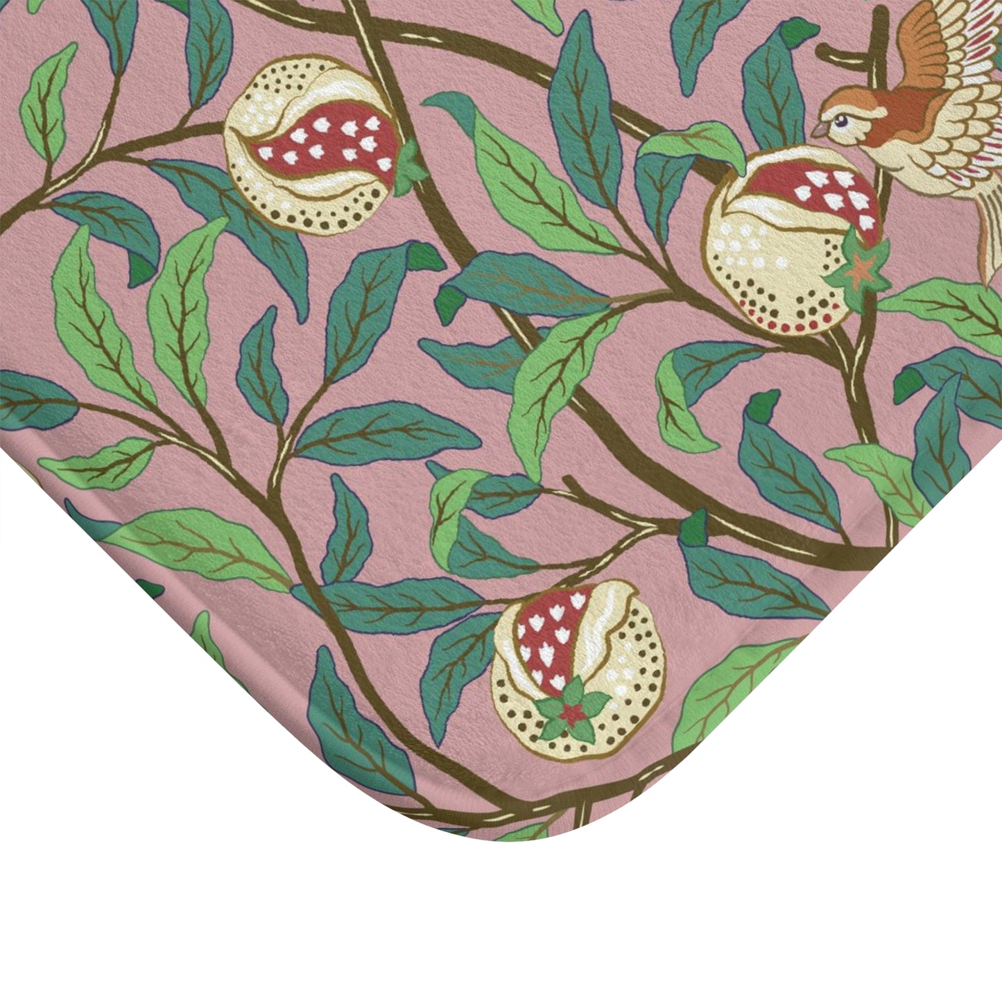 A rectangular microfibre bath mat with a William Morris floral pattern featuring birds and pomegranates in pink, green and white colours.