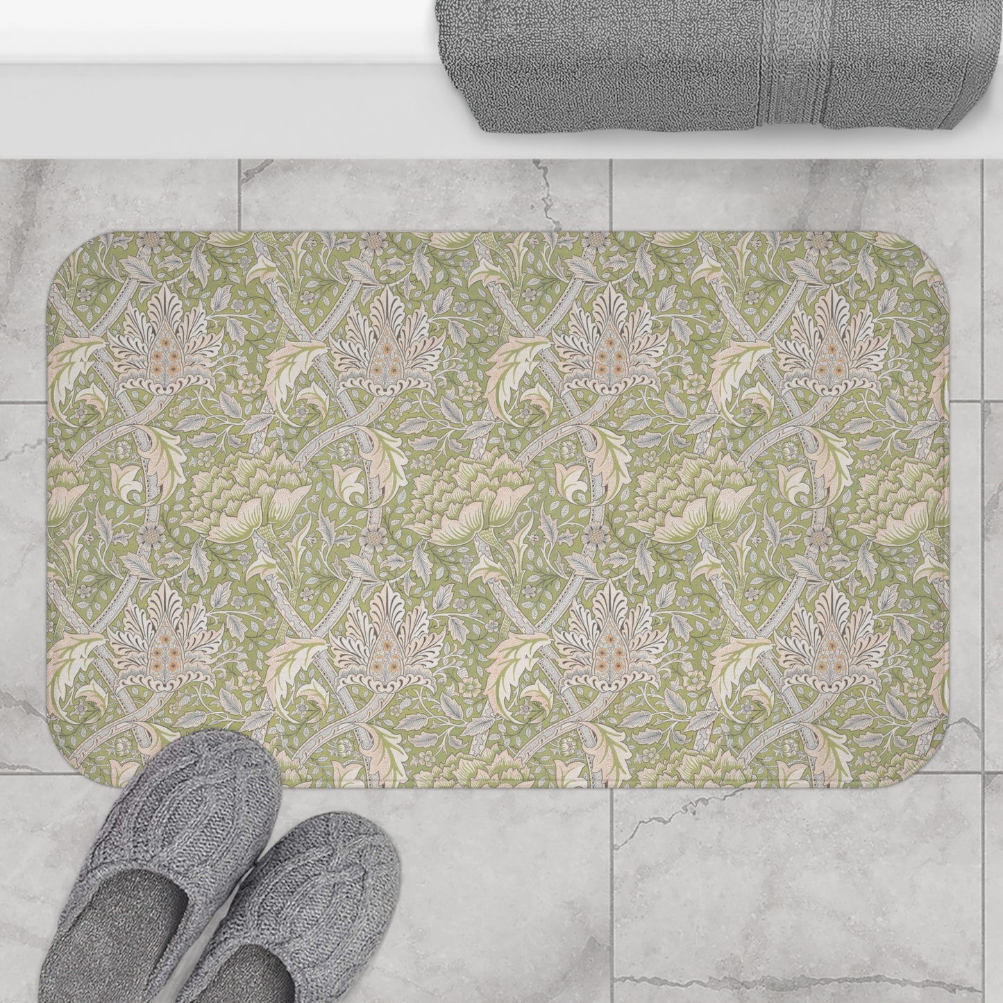 Patterned bath mat on a tiled floor with slippers and a towel.