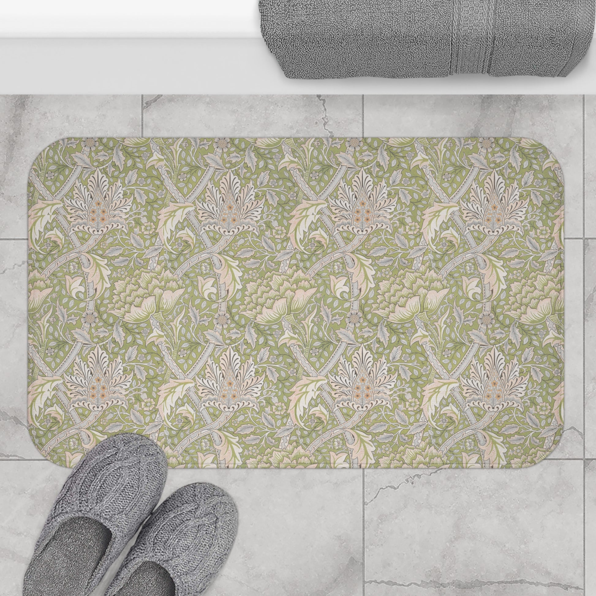 Patterned bath mat on a tiled floor with slippers and a towel.