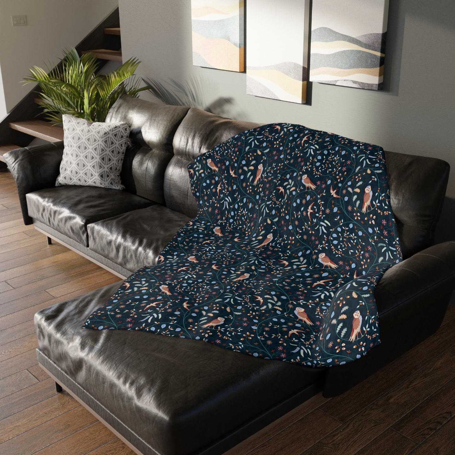 Patterned William Morris & Co blanket draped over a dark brown leather sofa in a living room.