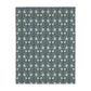 A rectangular blanket with a two-sided print featuring William Morris & Co floral patterns in shades of slate and green in a pattern called Pimpernel with a luxurious velveteen texture.