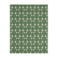 A rectangular blanket with a two-sided print featuring William Morris & Co floral patterns in shades of slate and green in a pattern called Pimpernel with a luxurious velveteen texture.