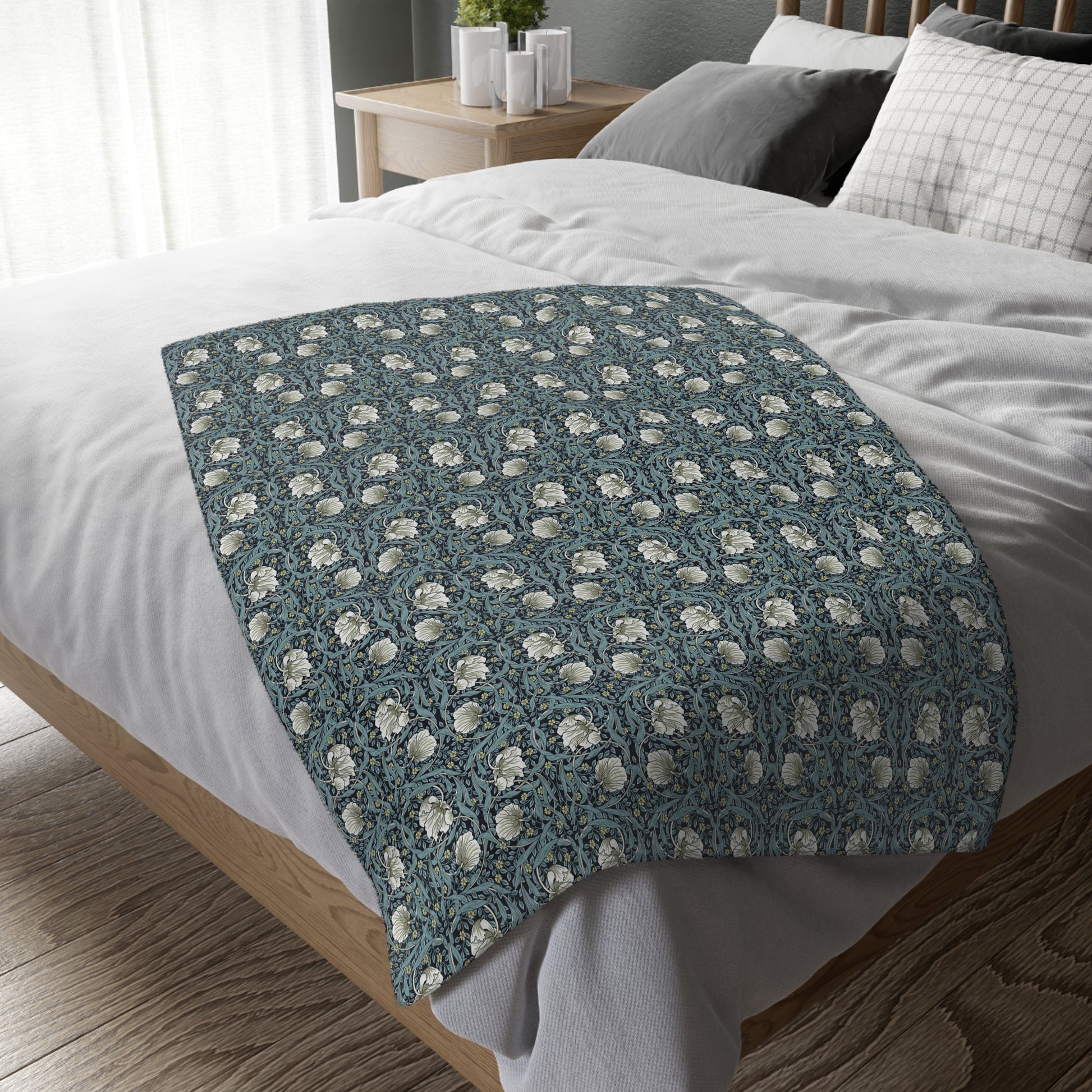 A rectangular blanket with a two-sided print featuring William Morris & Co floral patterns in shades of slate and green in a pattern called Pimpernel with a luxurious velveteen texture.