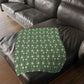 A rectangular blanket with a two-sided print featuring William Morris & Co floral patterns in shades of slate and green in a pattern called Pimpernel with a luxurious velveteen texture.