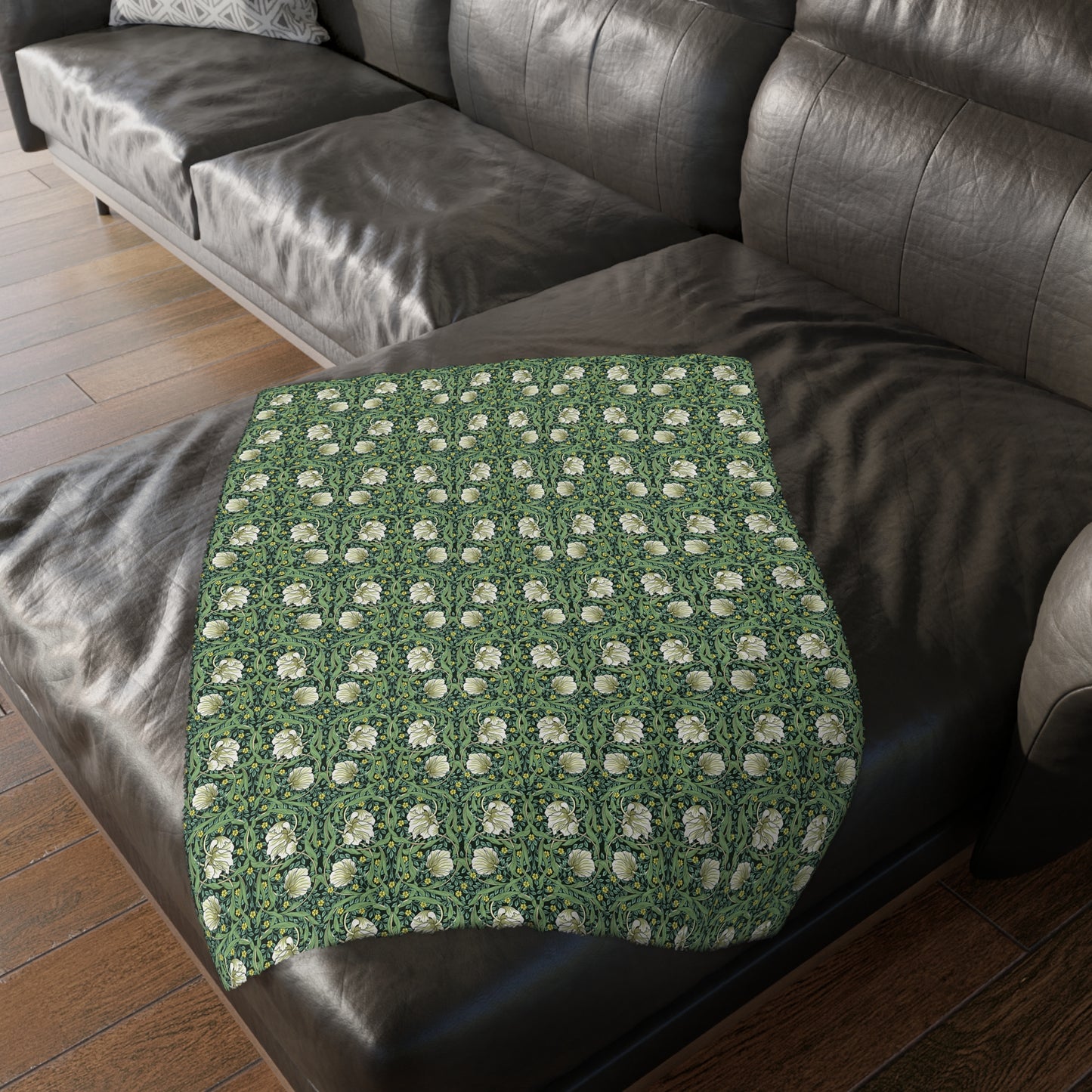 A rectangular blanket with a two-sided print featuring William Morris & Co floral patterns in shades of slate and green in a pattern called Pimpernel with a luxurious velveteen texture.