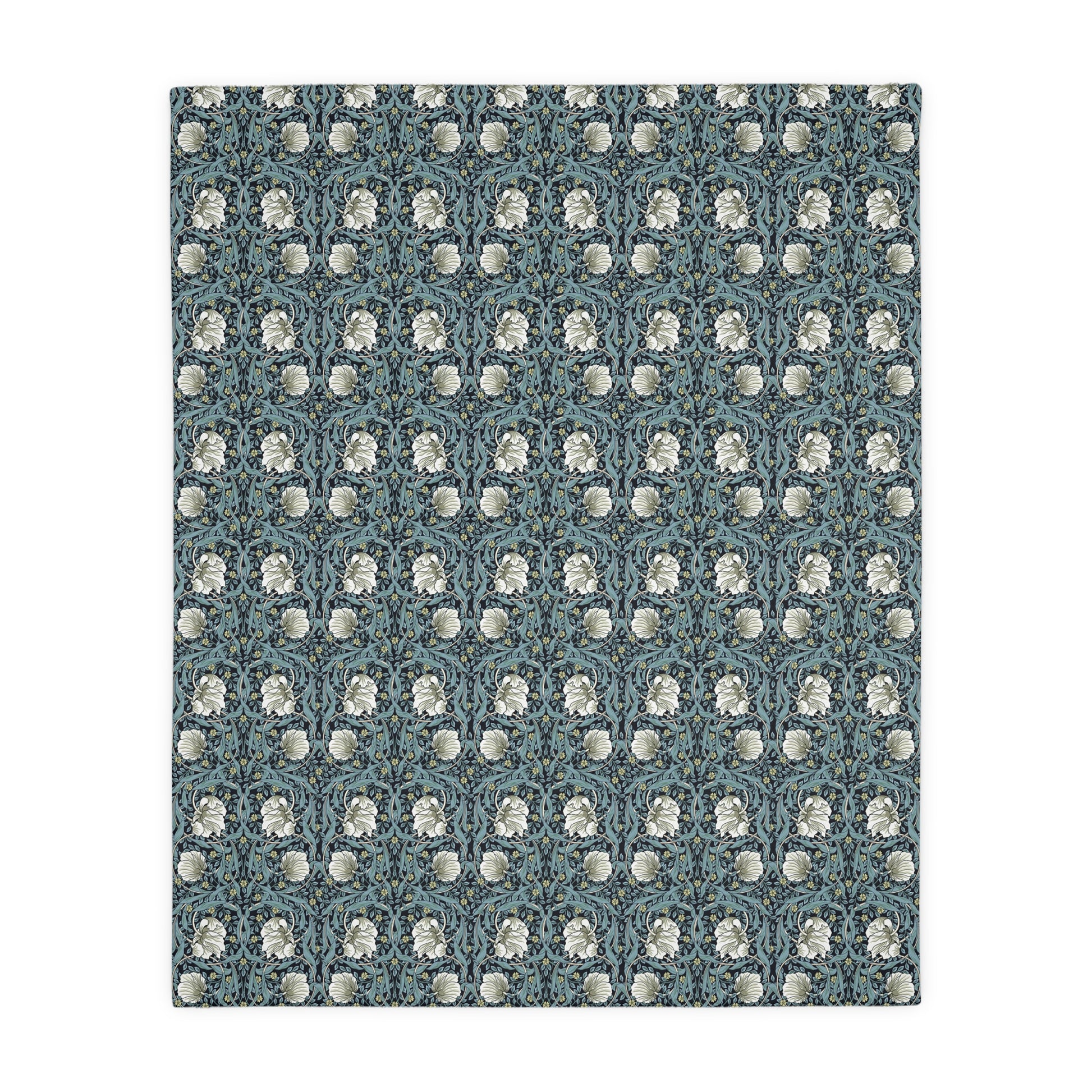 A rectangular blanket with a two-sided print featuring William Morris & Co floral patterns in shades of slate and green in a pattern called Pimpernel with a luxurious velveteen texture.