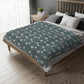 A rectangular blanket with a two-sided print featuring William Morris & Co floral patterns in shades of slate and green in a pattern called Pimpernel with a luxurious velveteen texture.
