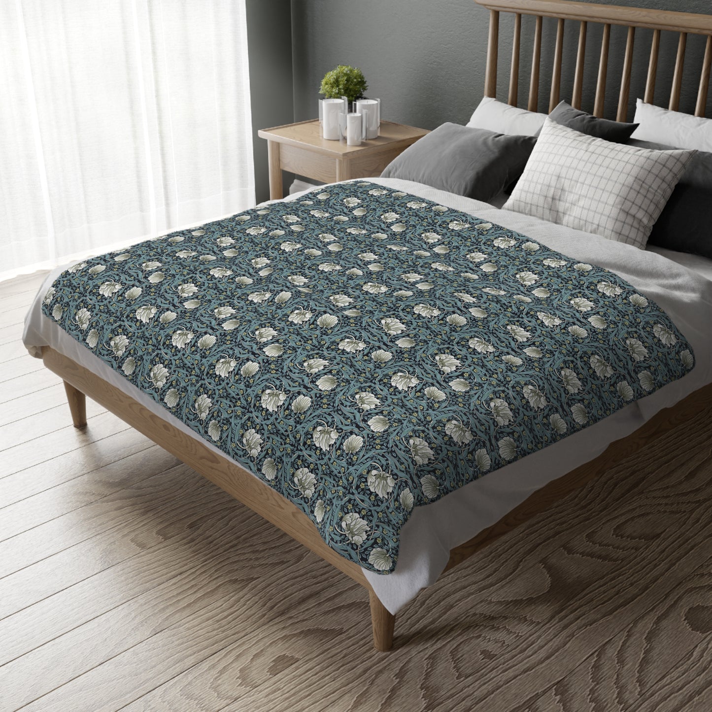 A rectangular blanket with a two-sided print featuring William Morris & Co floral patterns in shades of slate and green in a pattern called Pimpernel with a luxurious velveteen texture.