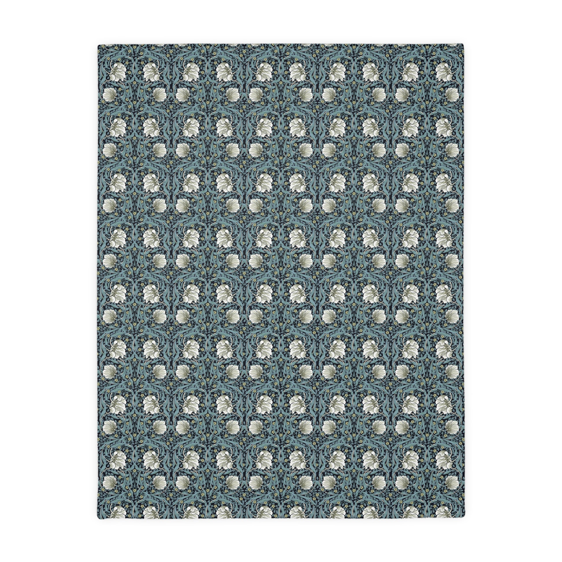 A rectangular blanket with a two-sided print featuring William Morris & Co floral patterns in shades of slate and green in a pattern called Pimpernel with a luxurious velveteen texture.