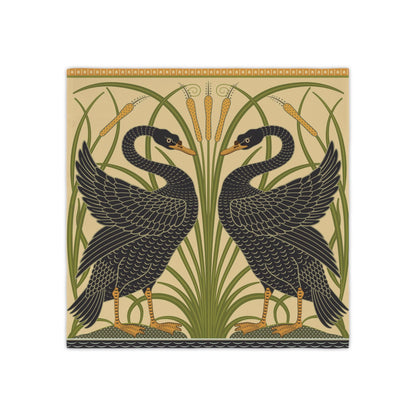 A square decorative table napkin featuring a symmetrical Art Deco style design of two black swans facing each other among tall green reeds and cattails on a warm beige background.