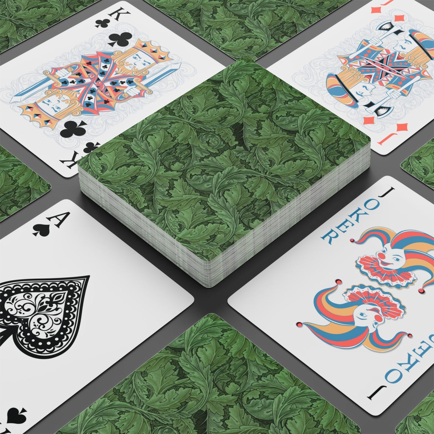 Playing cards with decorative green backs and colorful suits on a gray surface