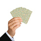 Hand holding a deck of playing cards with a floral pattern on a white background