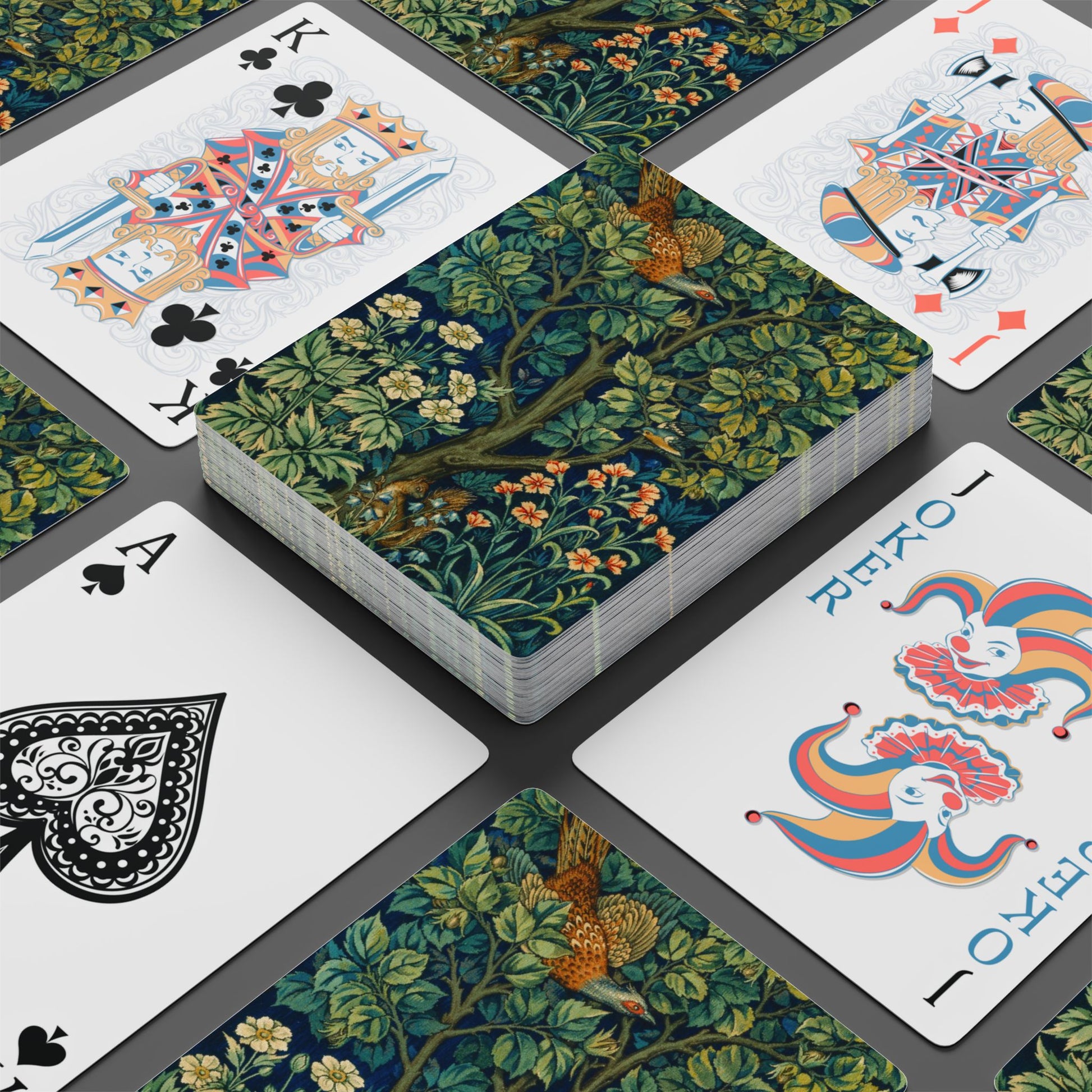 Playing cards with floral design and colorful jester card on a dark surface
