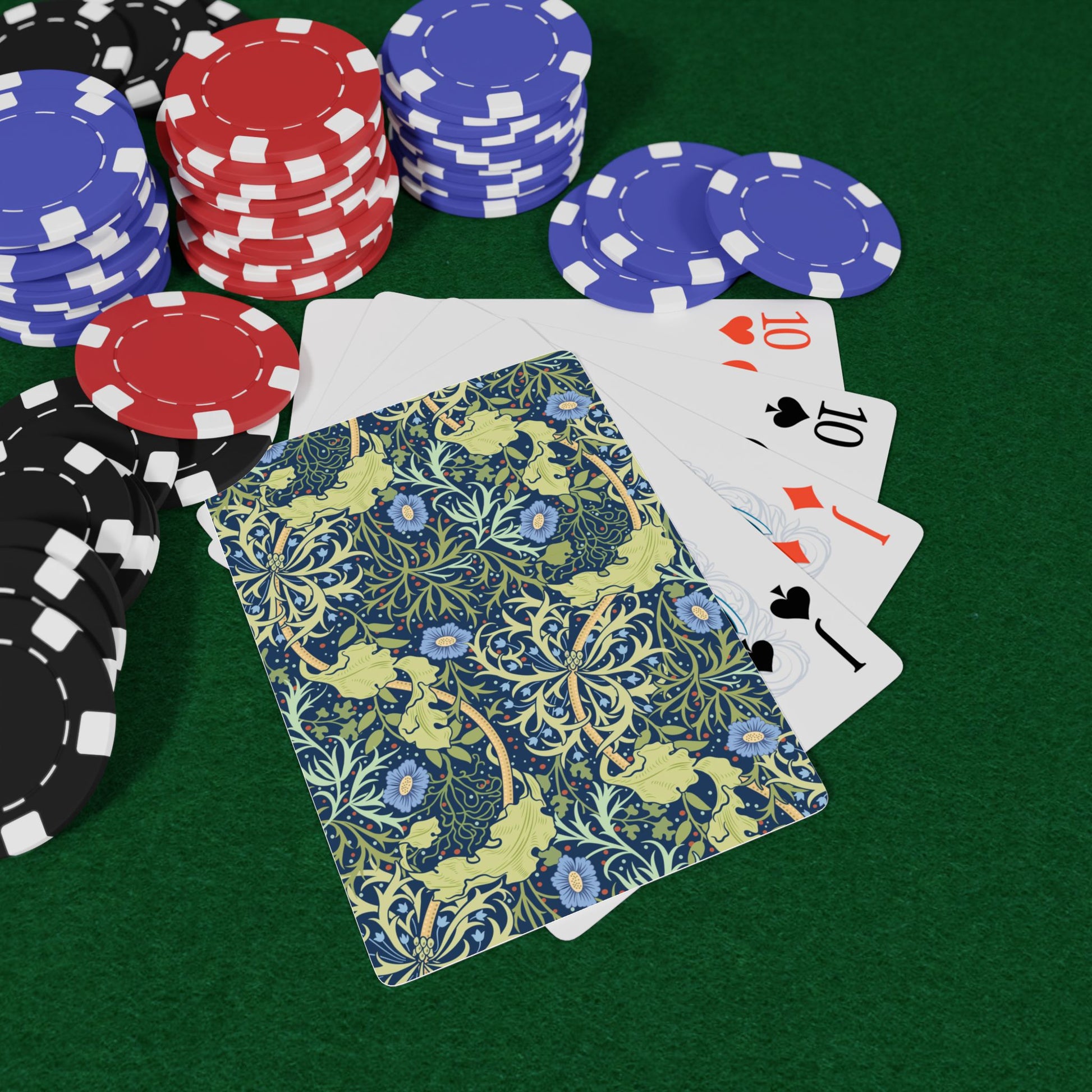 Playing cards with floral design and poker chips on a green surface