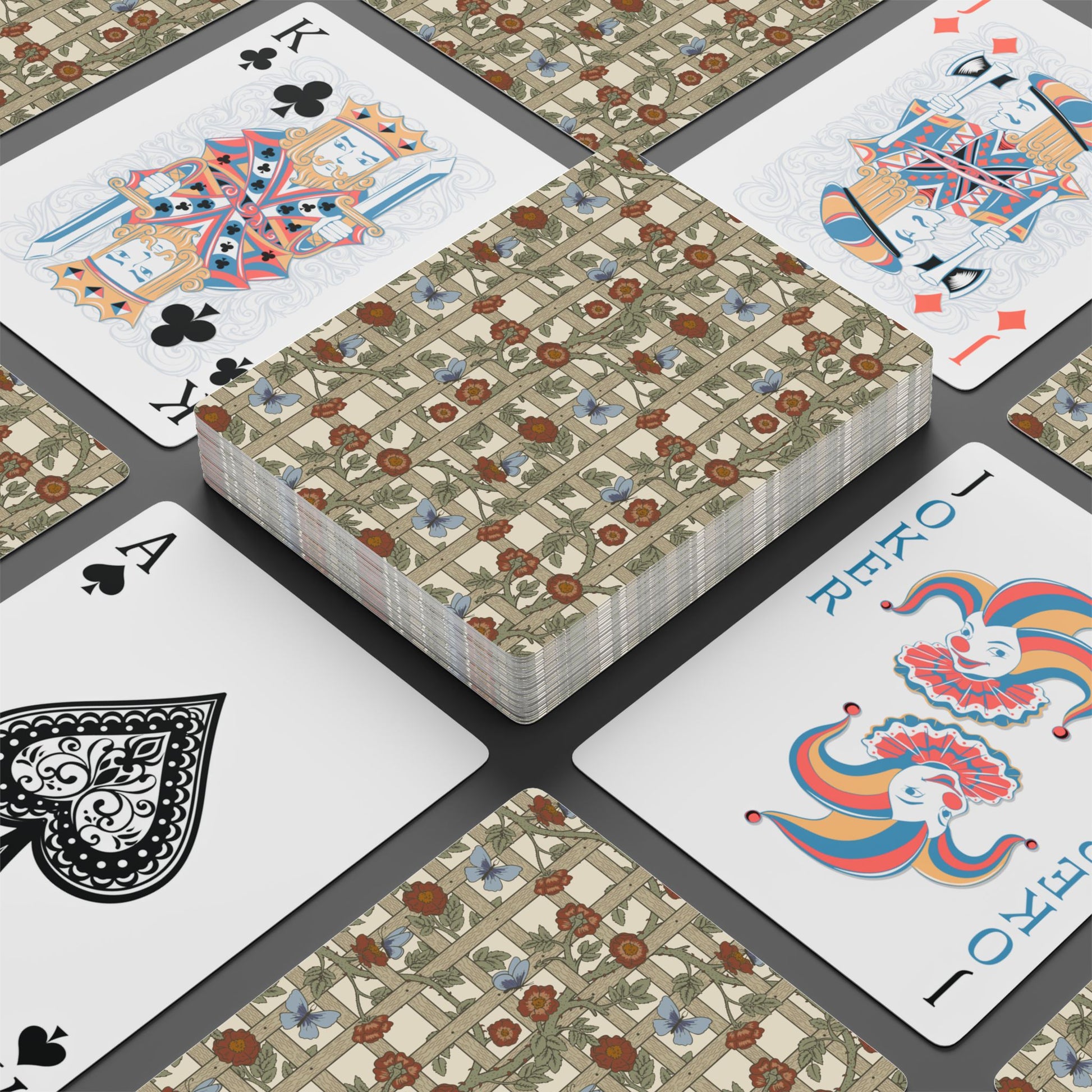 Playing cards with floral design and colorful joker card on a dark surface