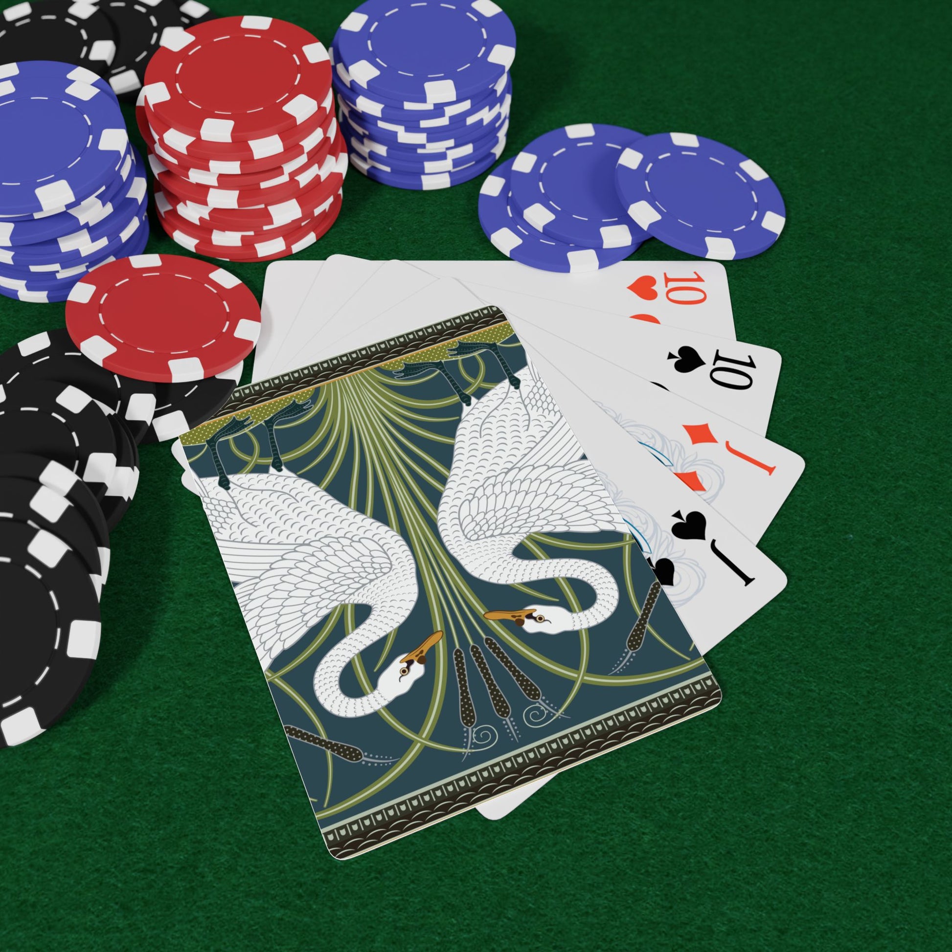 Playing cards with a swan design on a green table with poker chips.