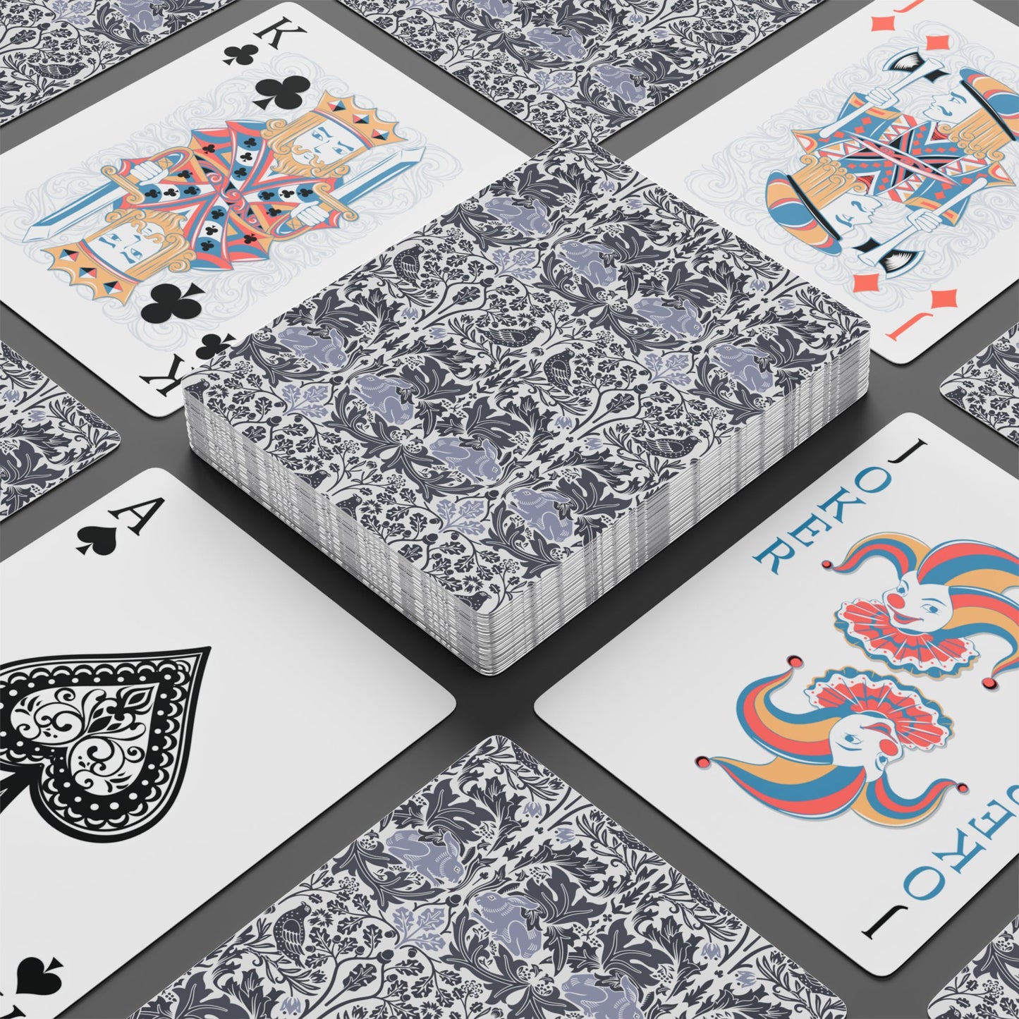 Playing cards with floral design and colorful joker card on a black surface