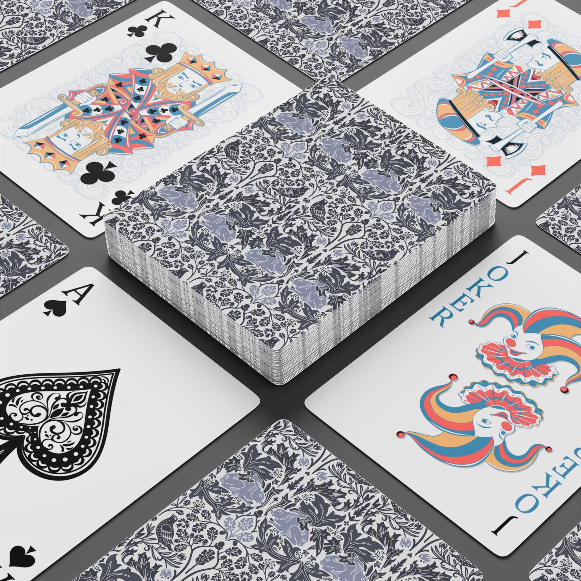 Playing cards with floral design and colorful joker card on a black surface