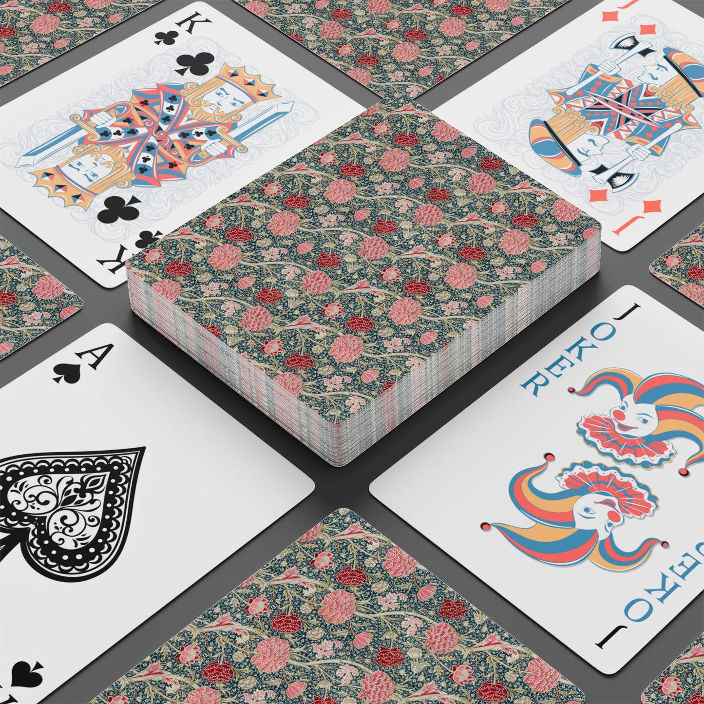 Playing cards with floral design and colorful joker card on a dark surface