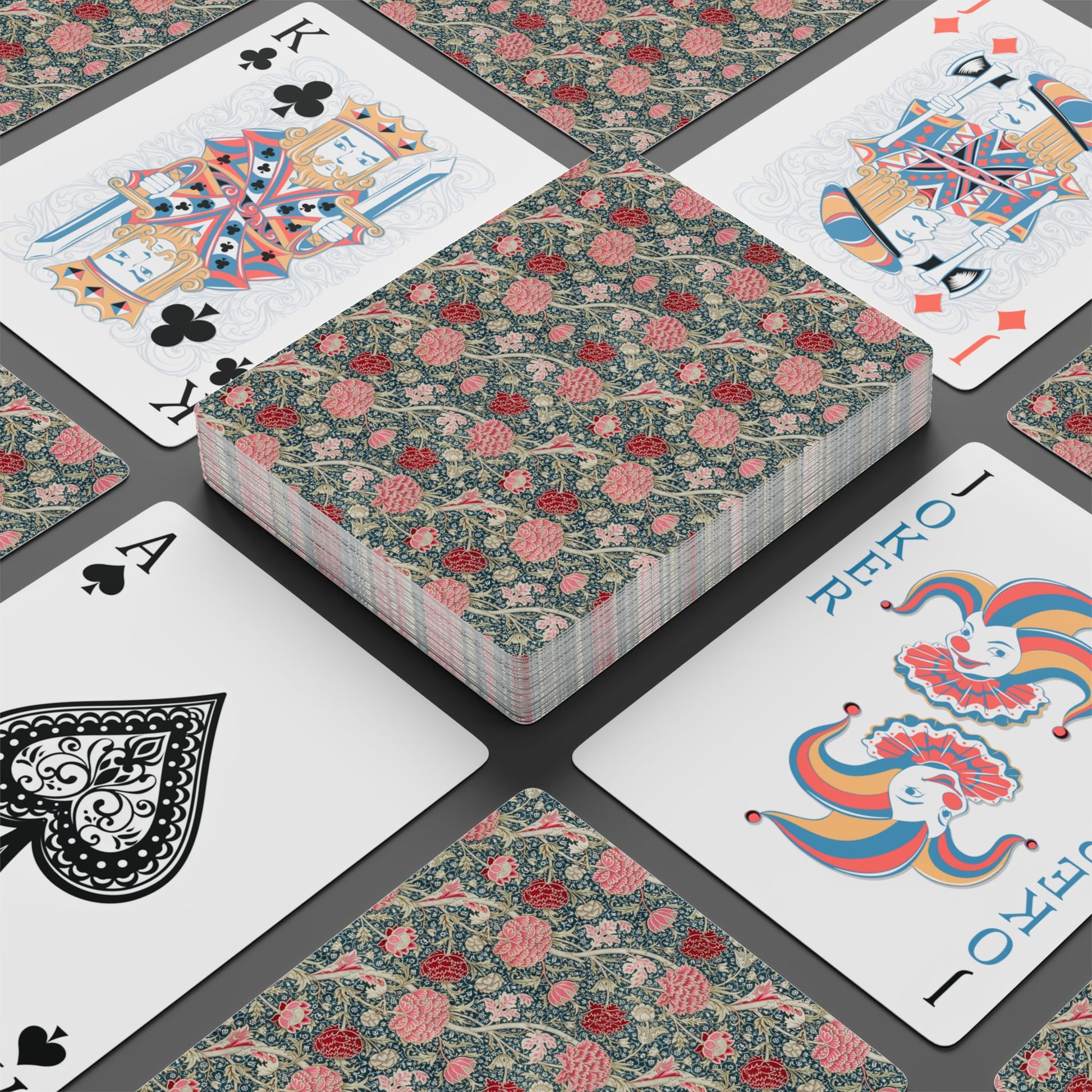 Playing cards with floral design and colorful joker card on a dark surface