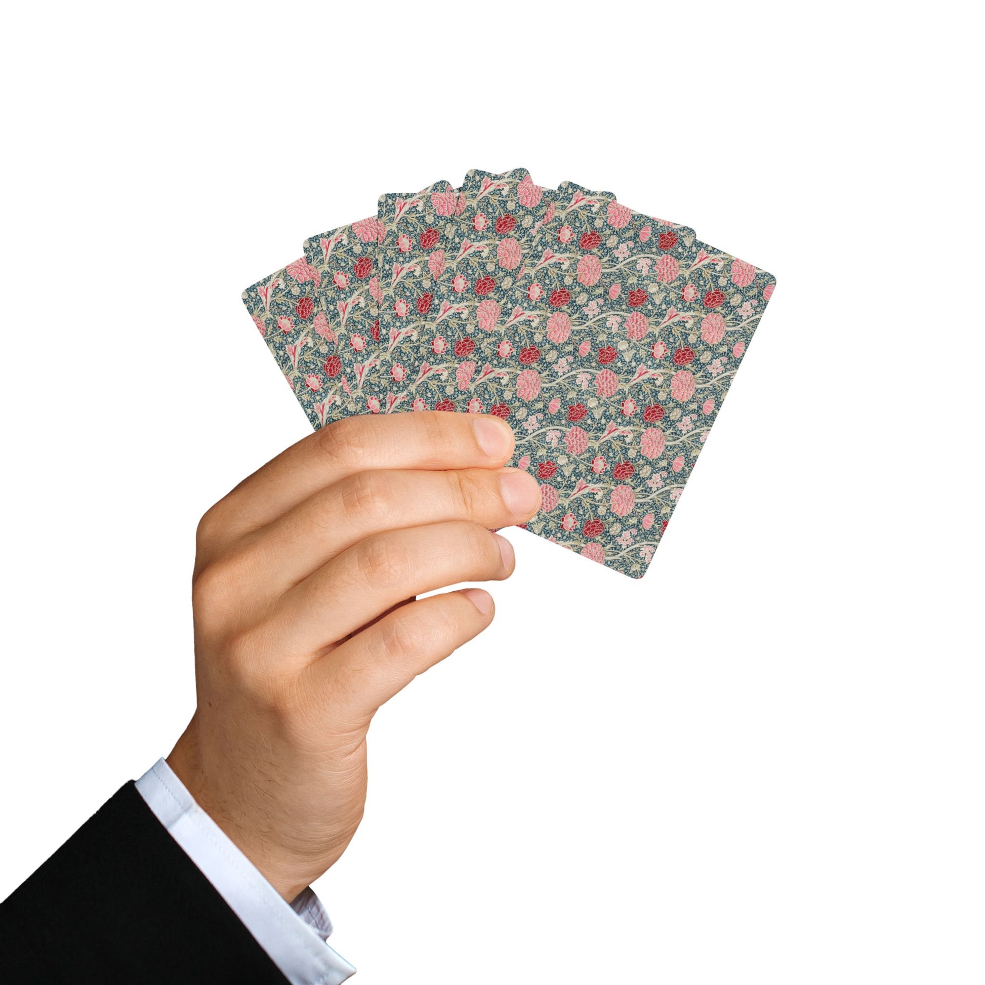 Hand holding a deck of floral-patterned playing cards against a white background