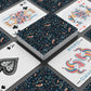 Playing cards with floral and abstract designs on a dark surface