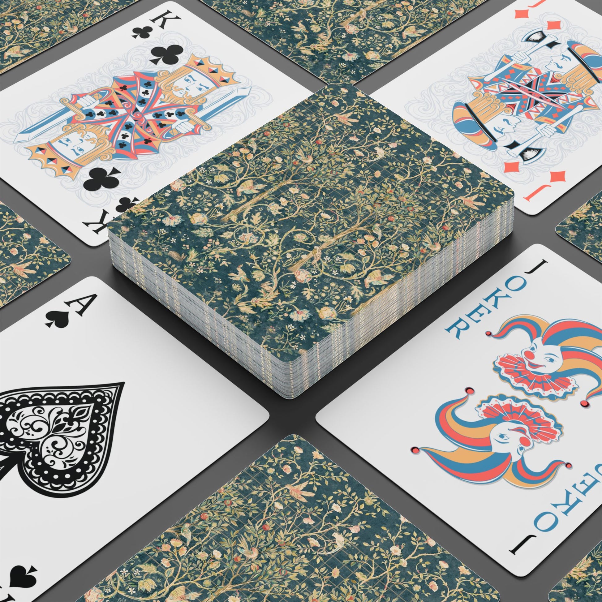 Playing cards with floral design and colorful joker card on a dark surface