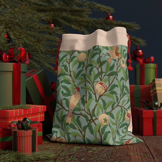 A Christmas Santa sack with a blue background featuring an intricate design with birds and pomegranates, with red drawstrings at the top.
