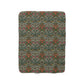 A cozy Sherpa Fleece Blanket with a geometric William Morris & Co pattern in a mix of dark and vibrant colours, laid out flat.