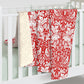 Red and white floral patterned blanket draped over a white crib.