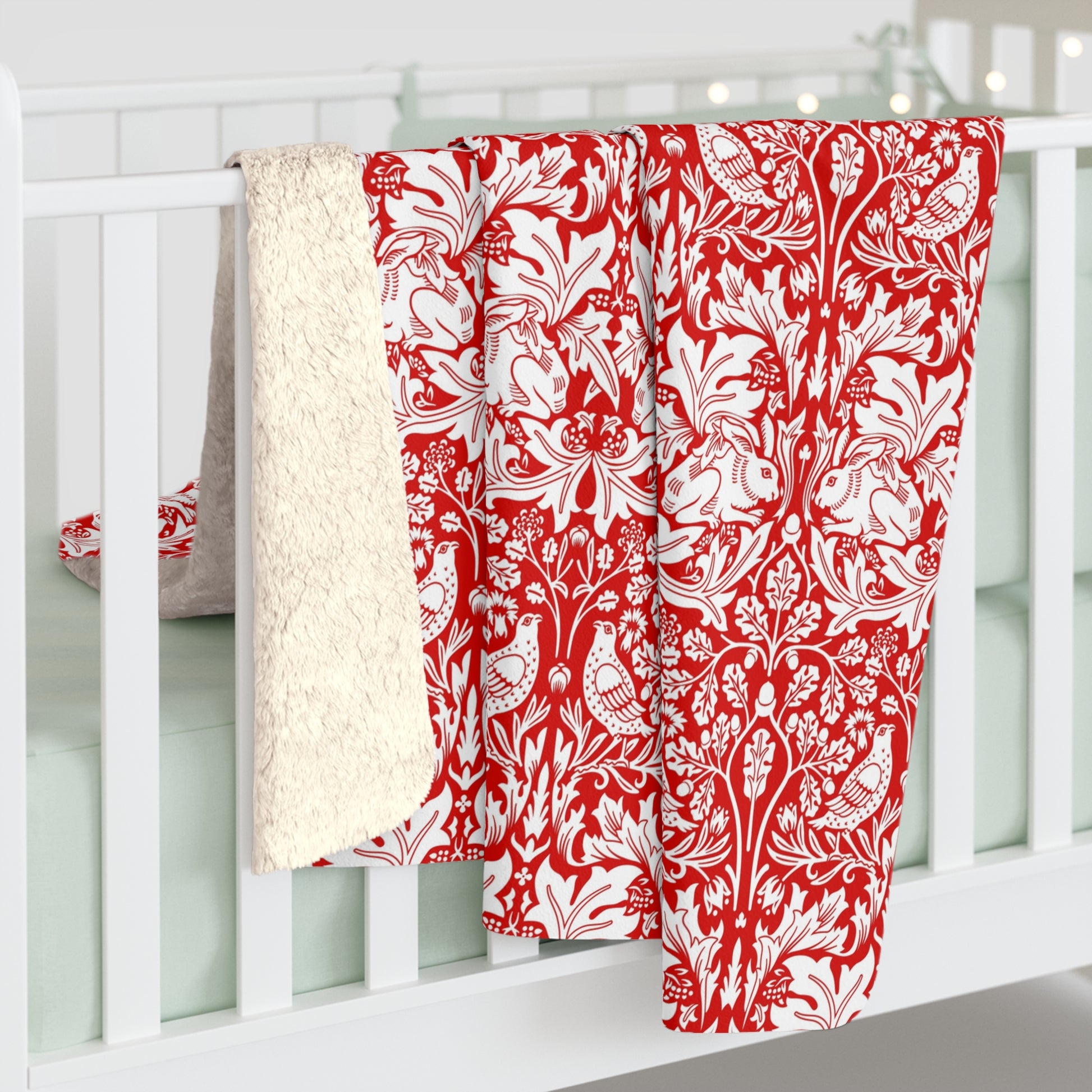 Red and white floral patterned blanket draped over a white crib.